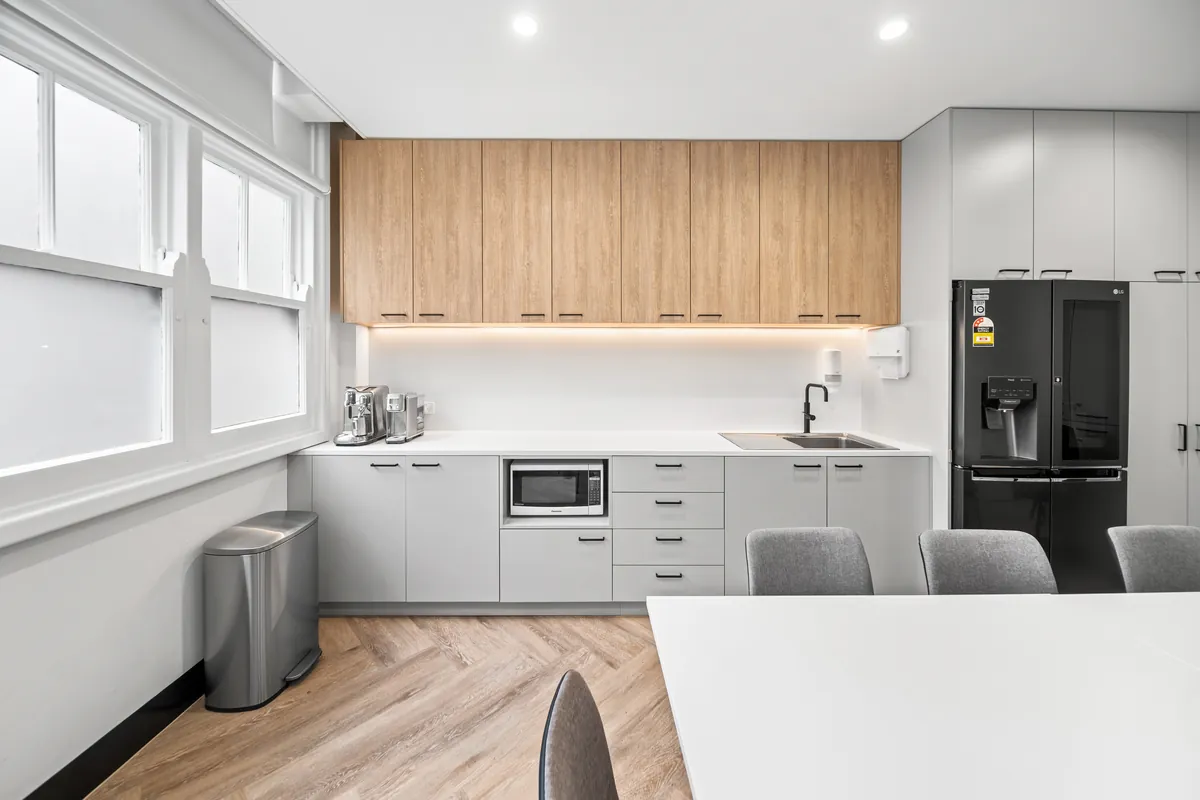 Staff kitchenette with timber joinery and stone benchtop at the SleepWise Clinic dental clinic fitout, Melbourne.